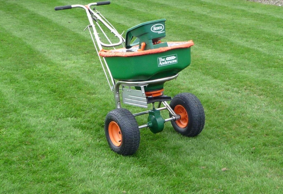 lawn feed applicator standing on a beautiful lush green lawn