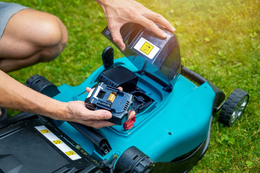 battery being removed from cordless lawn mower