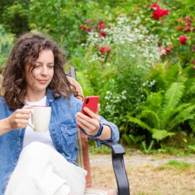 lady in garden watching lawn care videos on her mobile phone