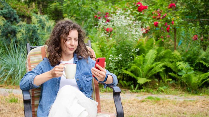 lady in garden watching lawn care videos on her mobile phone