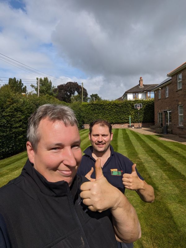 Robbie and Jason giving a thumbs up on a striped lawn